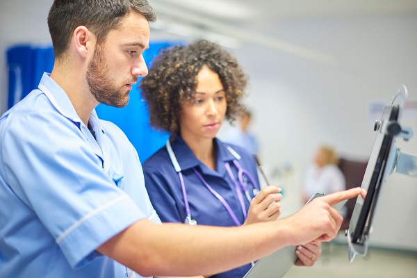 Digital tablets - a male nurse checks the dosage on his digital tablet supervised by his staff nurse