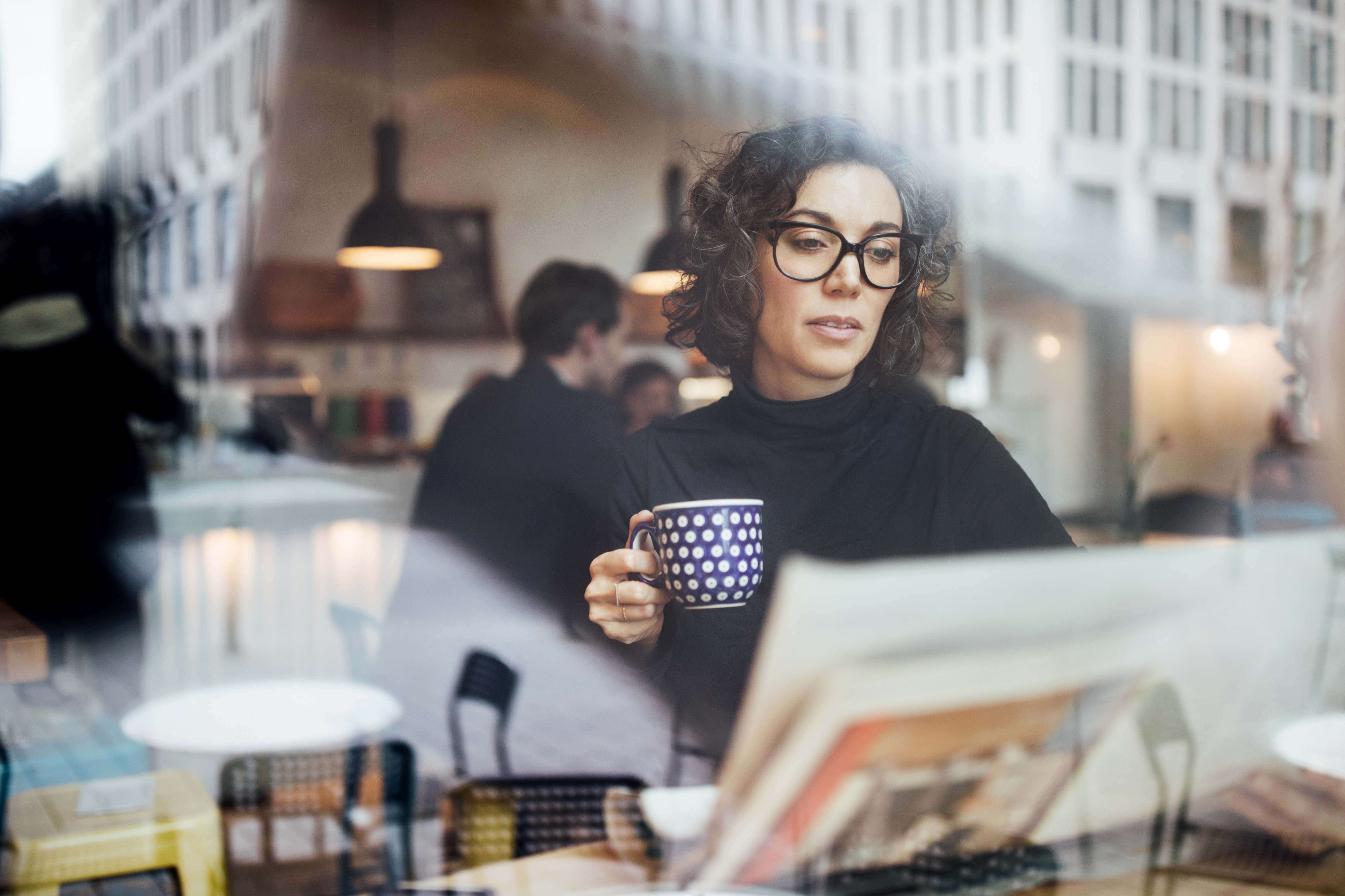 Female professional reading a newspaper in a cafe