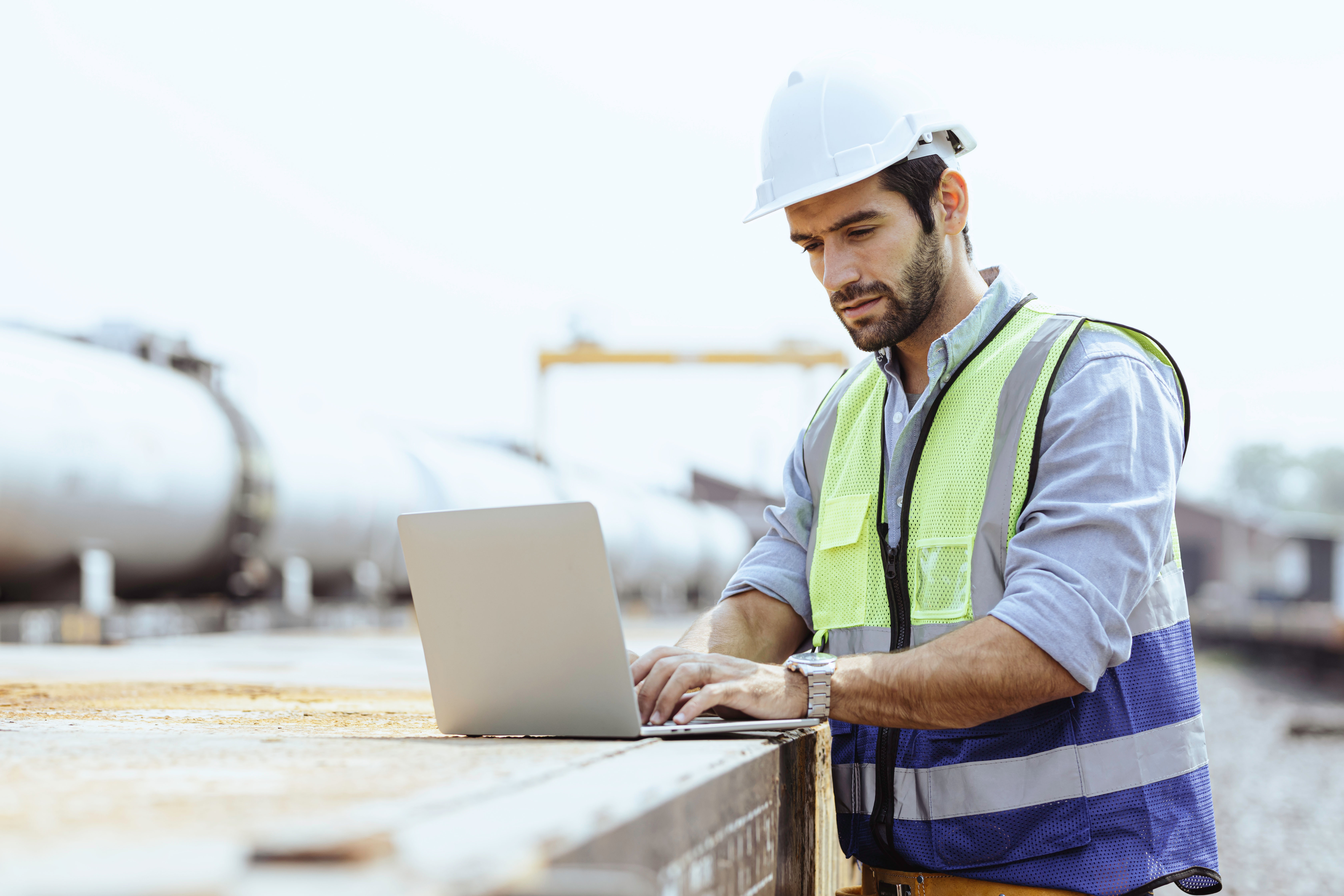 Heavy-duty industrial engineers stand in a pipeline manufacturing facility using digital tablet
