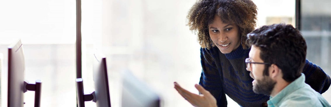 Two people in front of a computer screen.