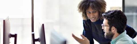 Two people in front of a computer screen.