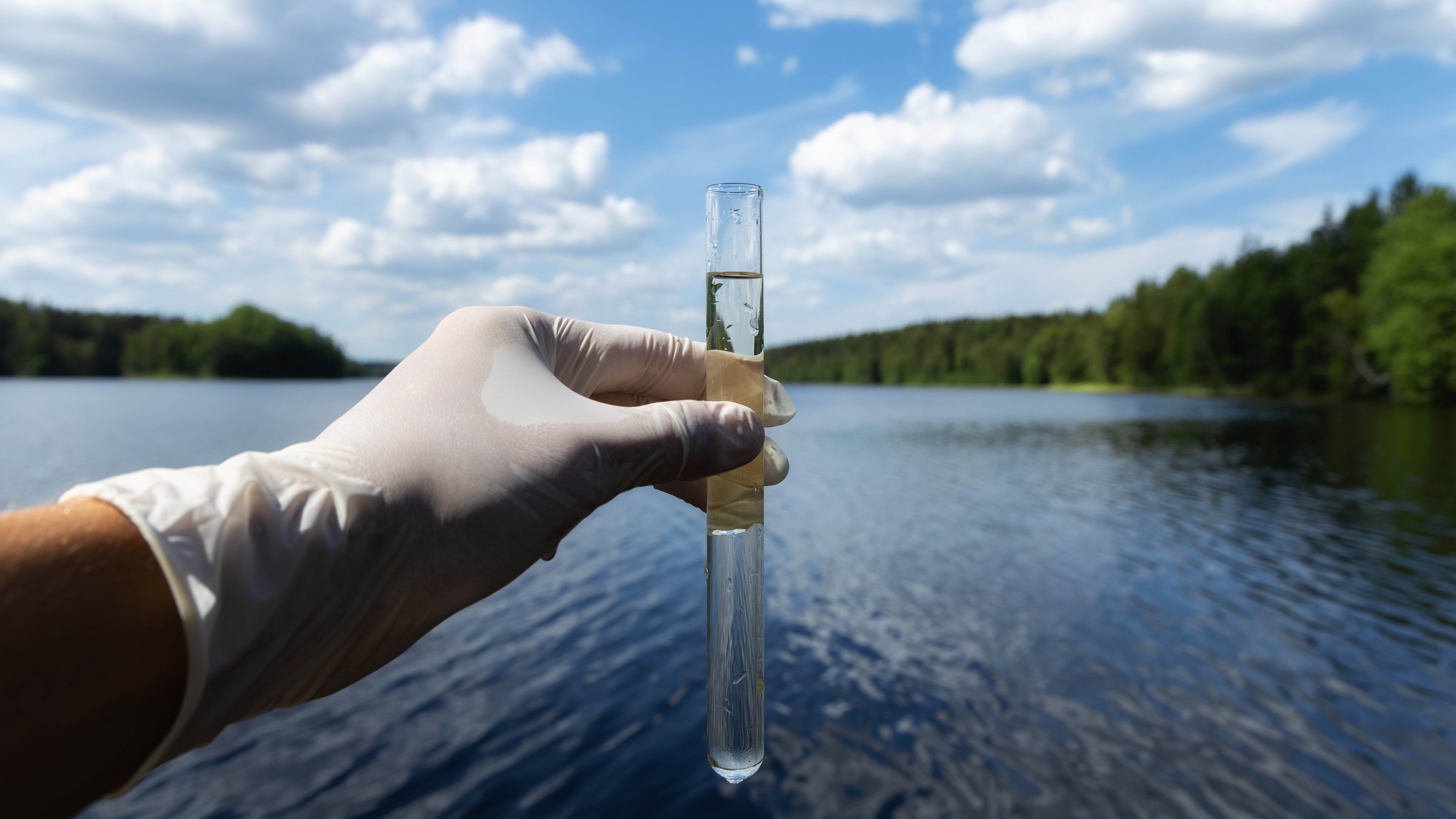 Laboratory technician collecting a water sample at a land-based aquaculture facility